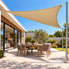 Shade sail in sand, a triangular sun and rain cover over a modern backyard dining setting