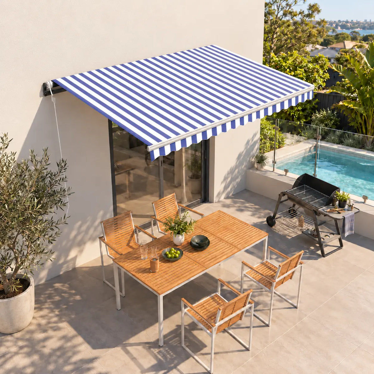Blue and white striped automatic retractable awning shading outdoor patio dining area with pool