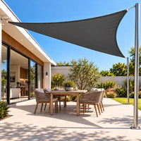 Shade sail in charcoal, a waterproof triangle over an outdoor dining table on a paved patio