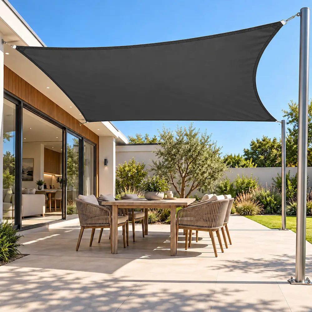 Shade sail in charcoal, a waterproof rectangle shading an outdoor dining table on a modern paved patio