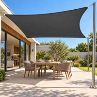Shade sail in charcoal, a waterproof rectangle shading an outdoor dining table on a modern paved patio