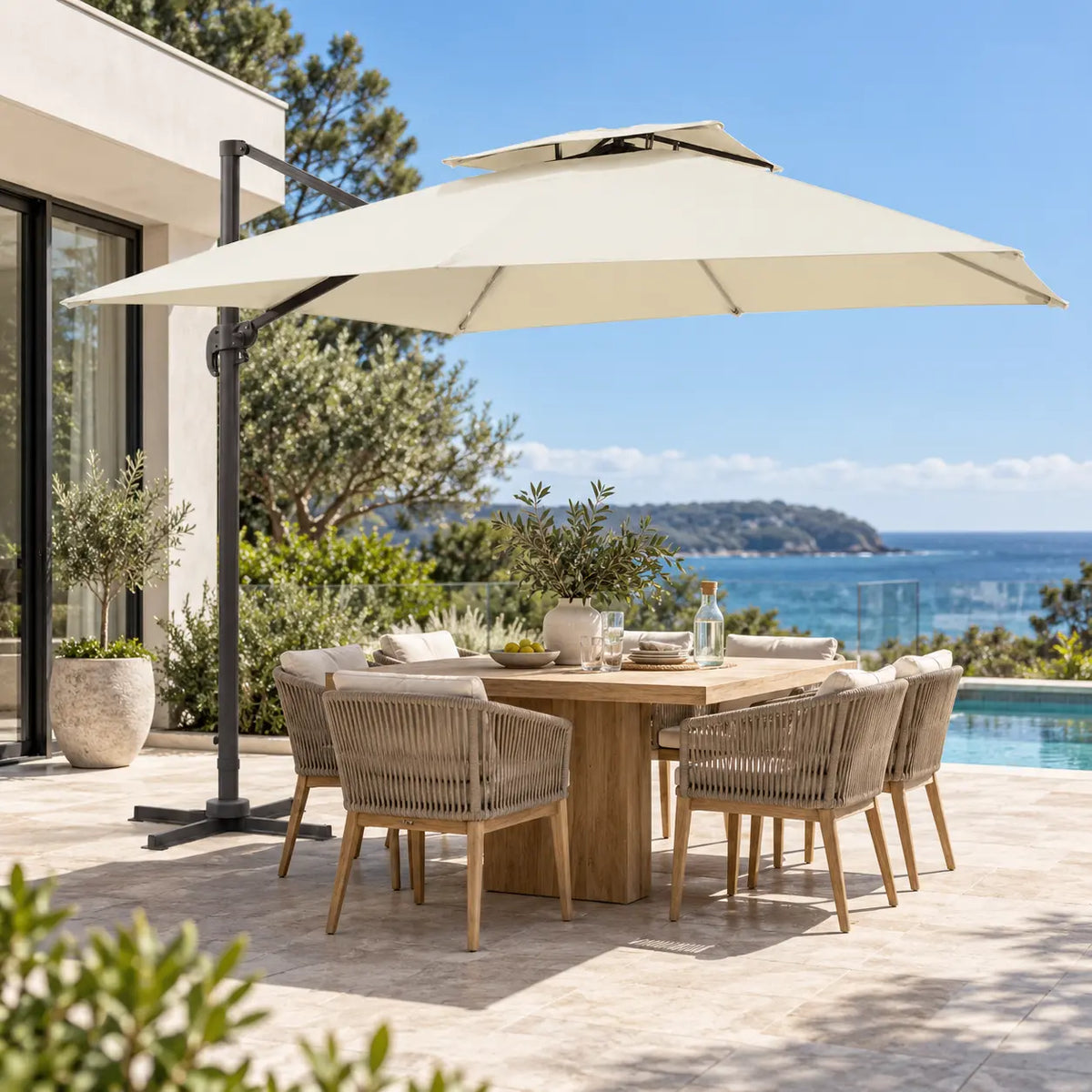 Cantilever umbrella 3x3 ivory over 8-seater teak outdoor dining set coastal terrace sea view modern home