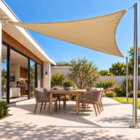 Shade sail in sand, a triangular sun and rain cover over a modern backyard dining setting