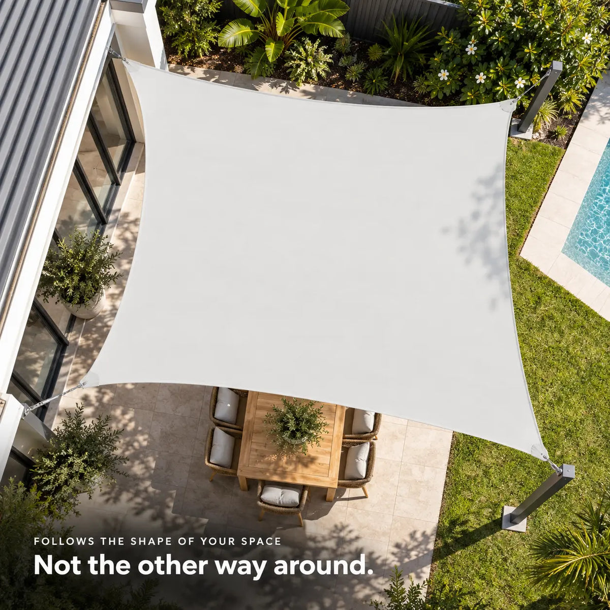 Rectangular white shade sail aerial view over stone patio with teak dining set and pool Image