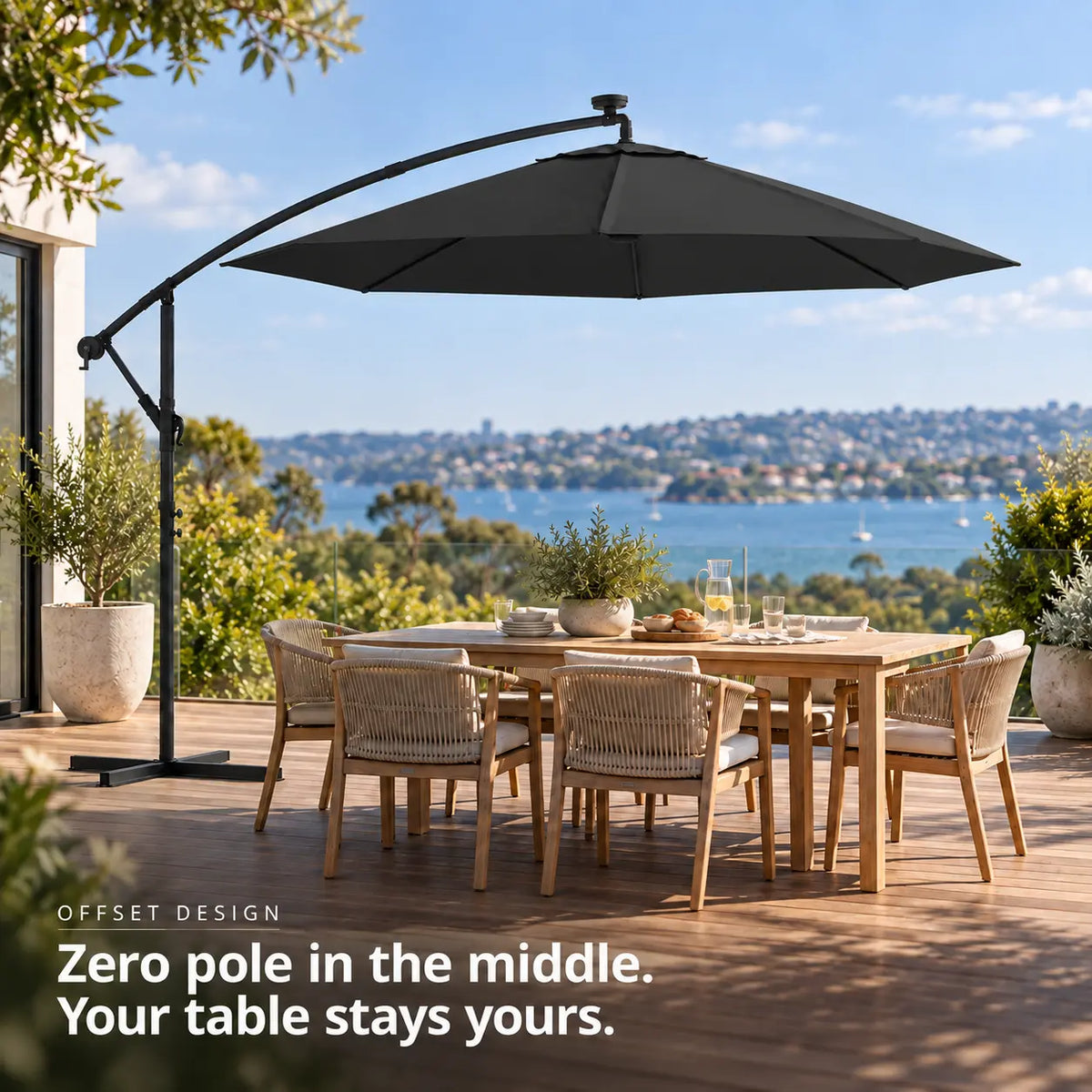 Round cantilever umbrella 3m black solar LED offset design no centre pole 6-seater teak dining table wooden deck coastal sea view