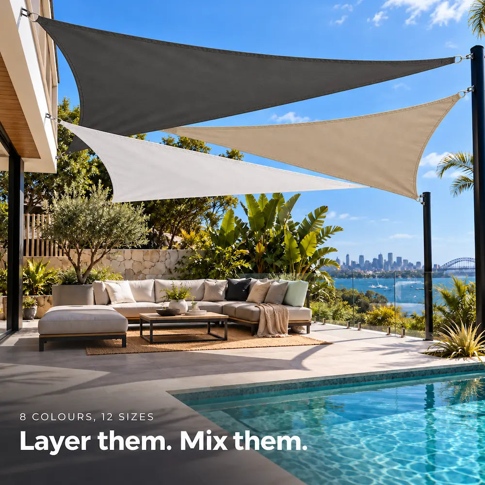 Shade sail trio of charcoal, sand and white triangles layered over a pool lounge with harbour views