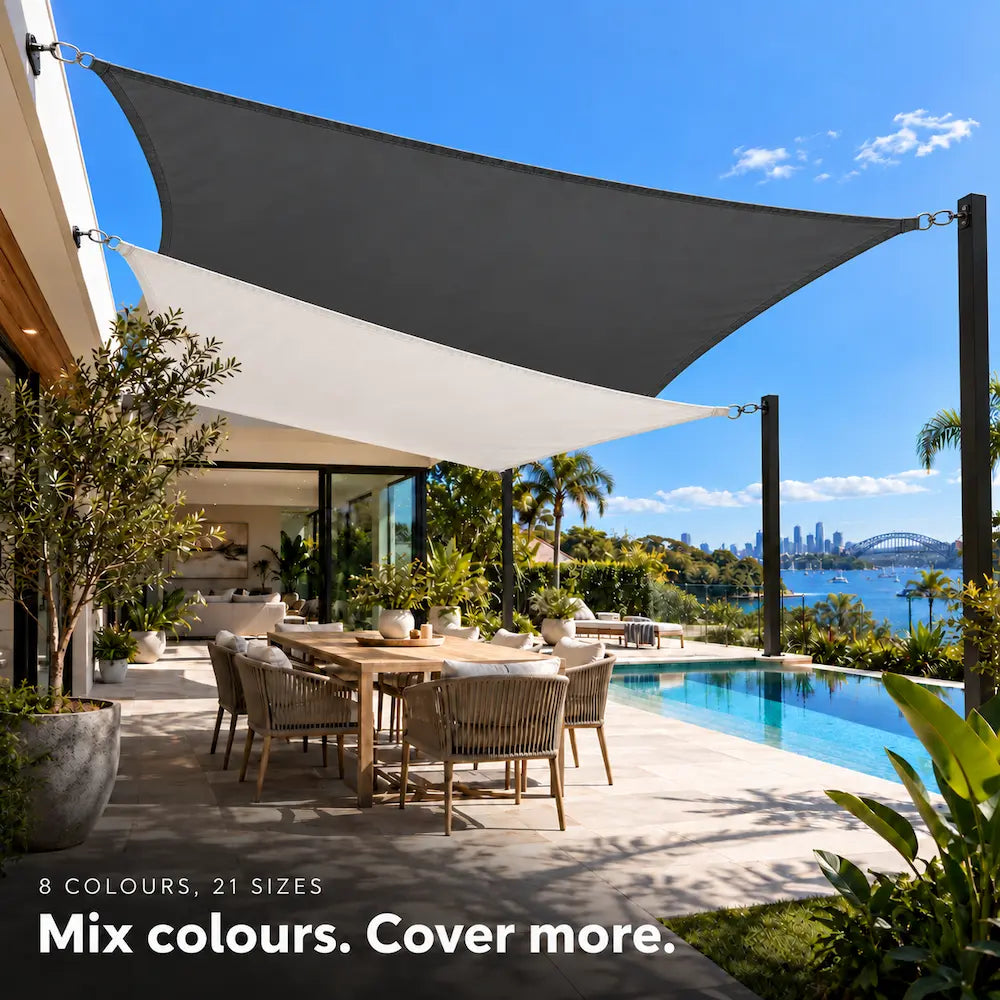 Shade sail pair in charcoal and white over a poolside dining area with harbour views