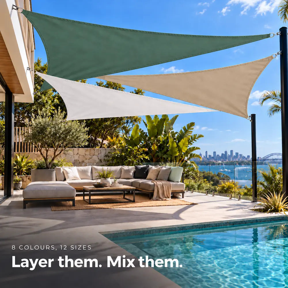 Shade sail layered in forest green, white and sand, triangular sails over a tropical pool lounge
