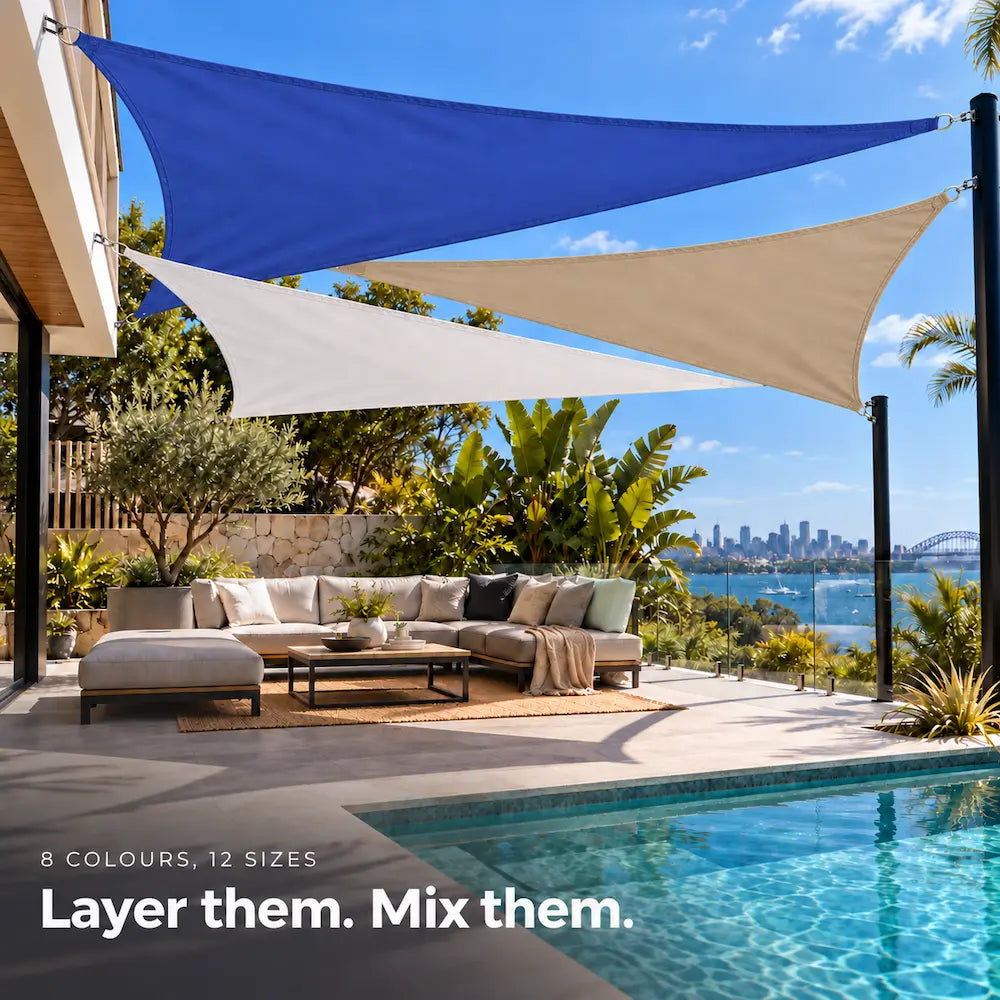 Shade sail design in ocean blue, white and sand triangles over a poolside sofa with harbour views