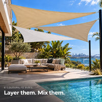 Shade sail layers in sand and white, three triangle sails over an outdoor sofa by the pool