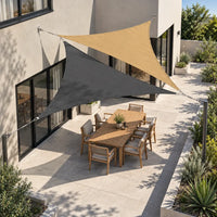 Shade sail charcoal and sand triangles fixed to the house wall and posts above a patio dining table