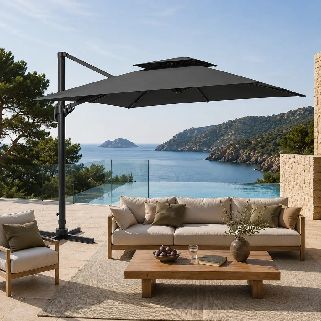 Anthracite cantilever umbrella providing shade over a teak outdoor lounge overlooking a coastal sea view and infinity pool