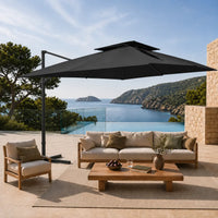 Black cantilever umbrella providing shade over a teak outdoor lounge setting on a poolside terrace overlooking a coastal bay