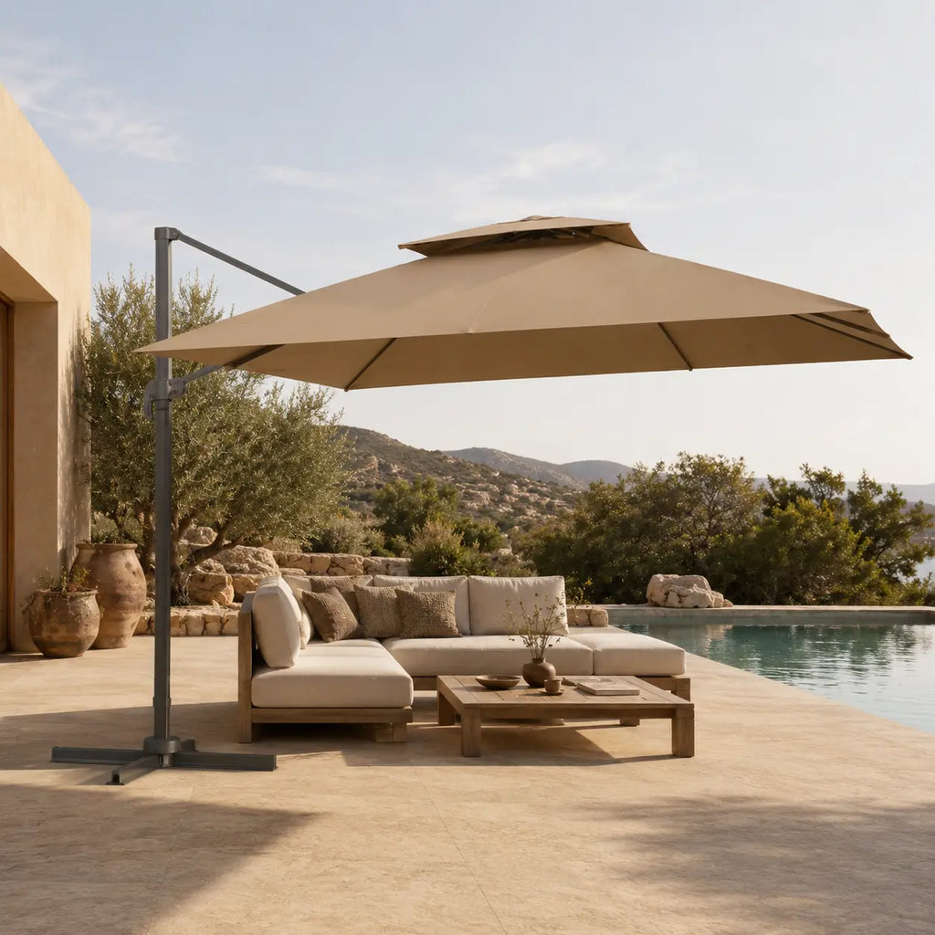 Rectangular taupe cantilever umbrella providing shade over an outdoor lounge beside a pool in a Mediterranean setting