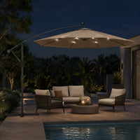 Round cantilever umbrella 3m Taupe with solar LED lights on over rope lounge set beside pool at night – Meltem