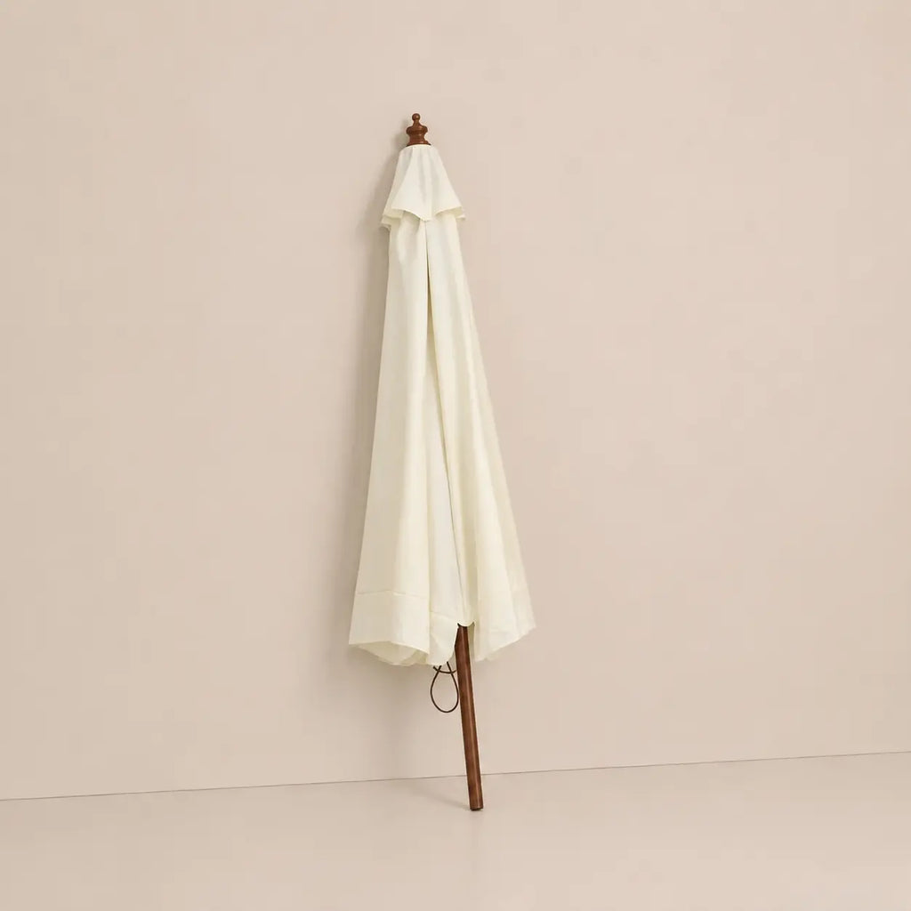Sand white market umbrella folded closed with hardwood pole and carved wooden finial