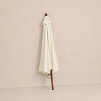 Sand white market umbrella folded closed with hardwood pole and carved wooden finial