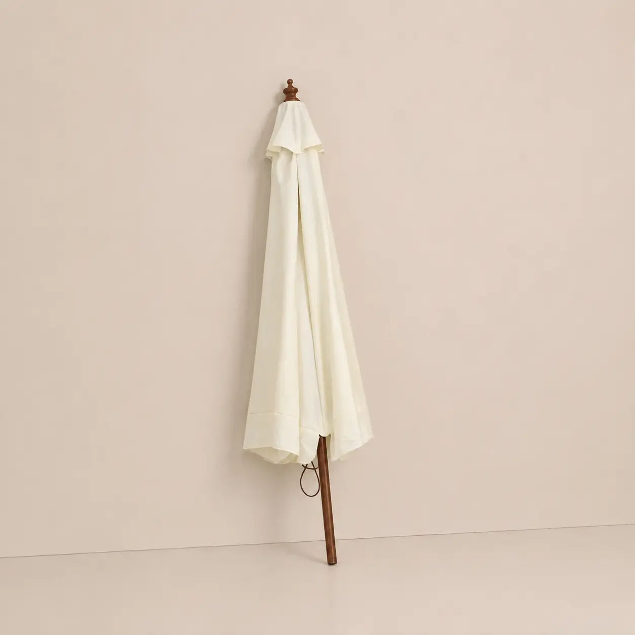 Sand white market umbrella folded closed with hardwood pole and carved wooden finial