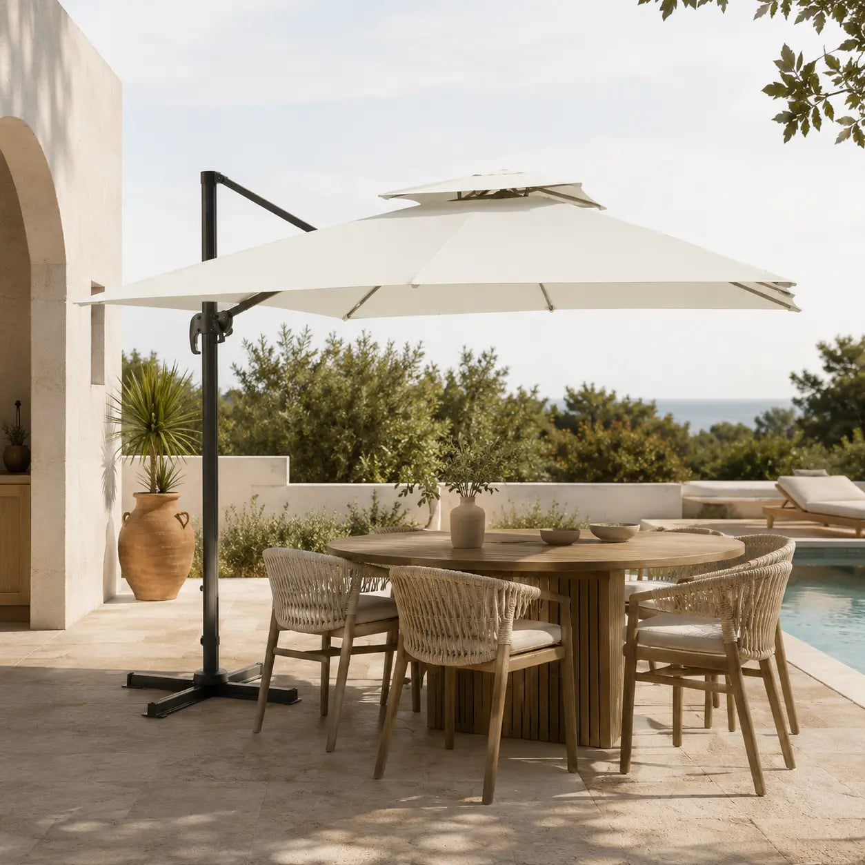 Ivory cantilever umbrella 3x3m with vented double canopy shading an outdoor dining table on a poolside terrace