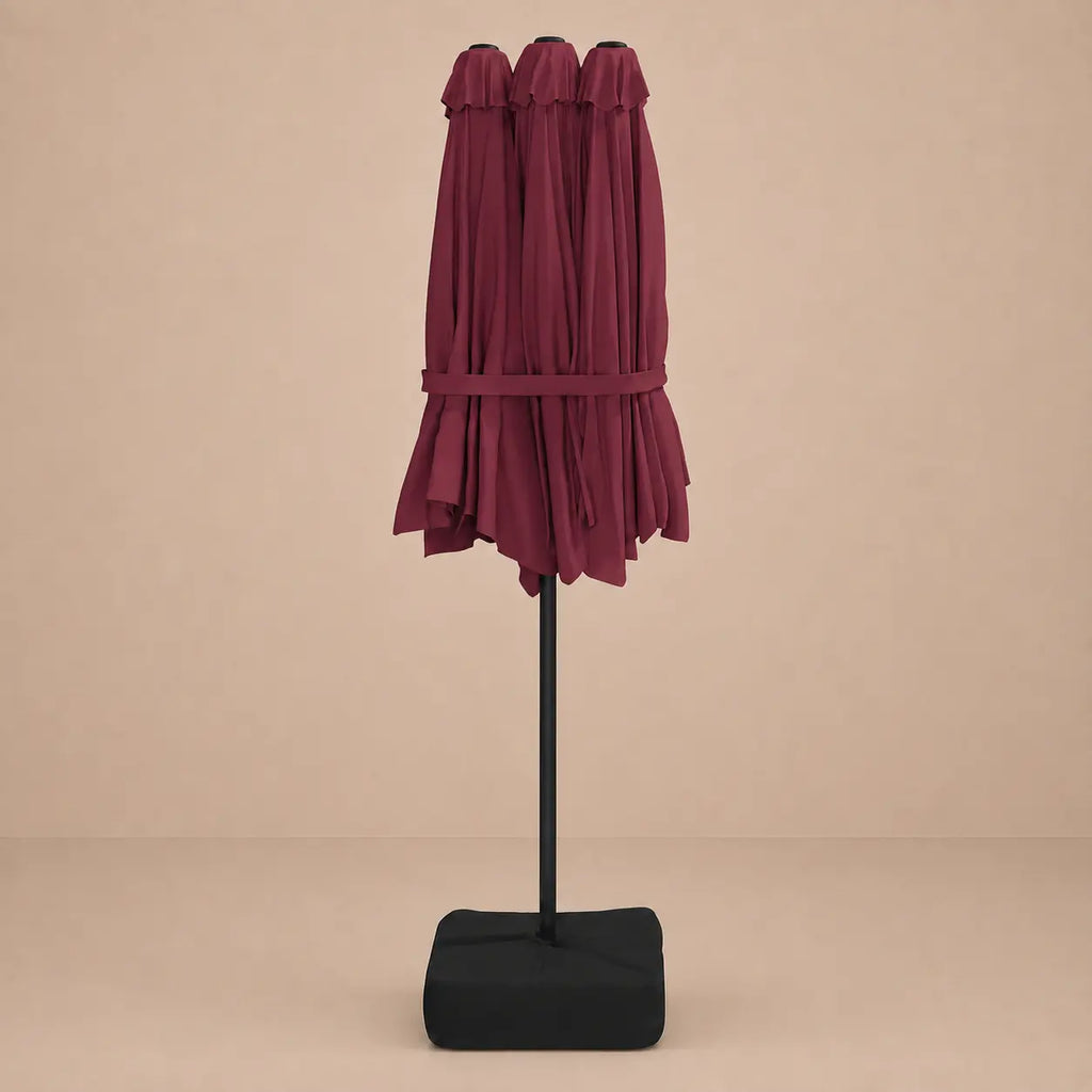 Bordeaux double canopy market umbrella folded closed on black aluminium pole with square weighted base