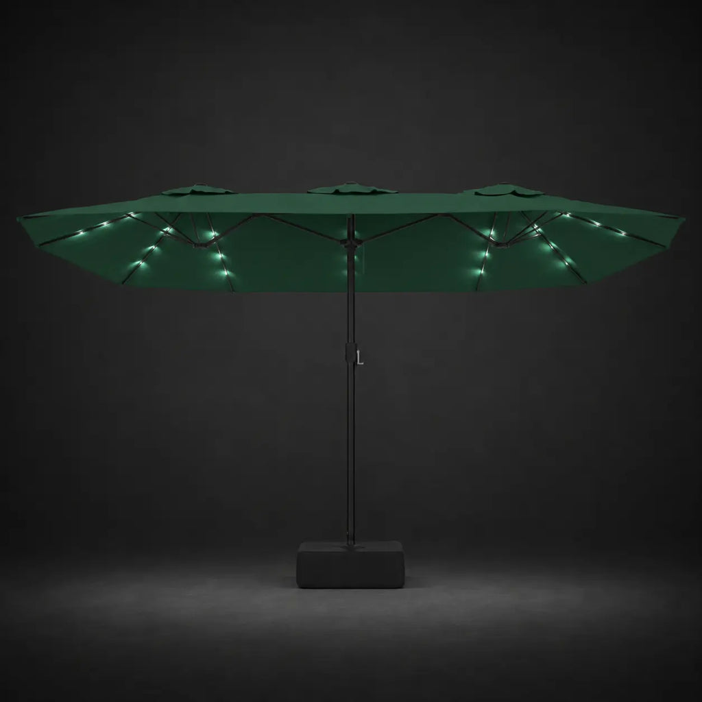Green double canopy market umbrella with integrated LED lights illuminated at night on a dark background