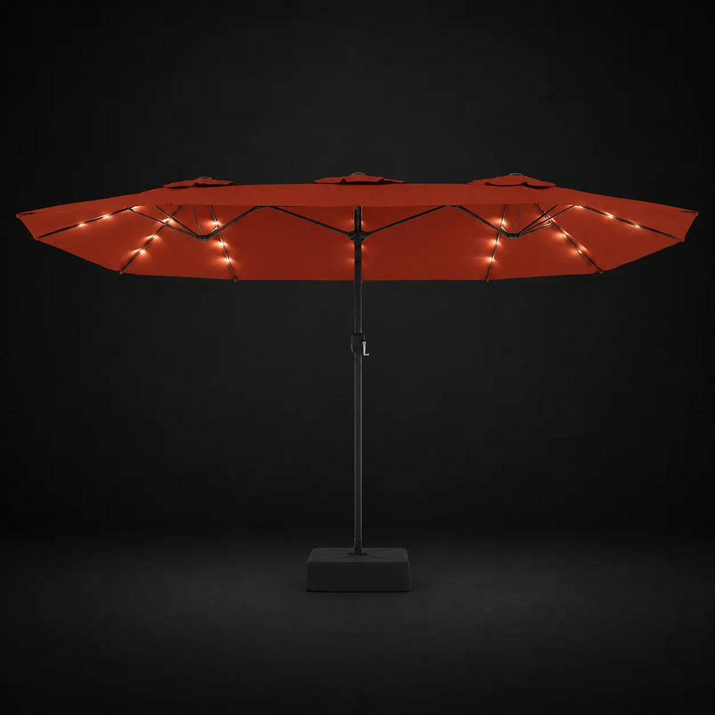 Terracotta double canopy market umbrella with integrated LED lights illuminated at night on a dark background