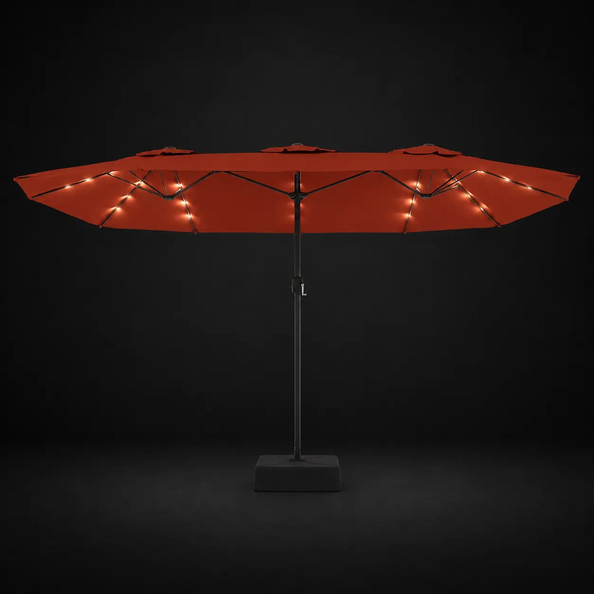 Terracotta double canopy market umbrella with integrated LED lights illuminated at night on a dark background