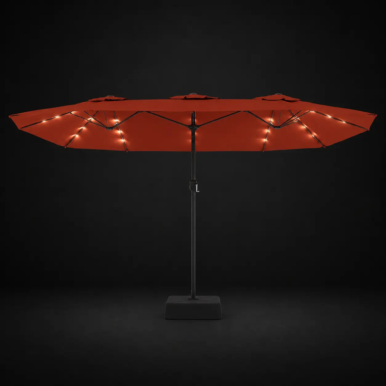 Terracotta double canopy market umbrella with integrated LED lights illuminated at night on a dark background