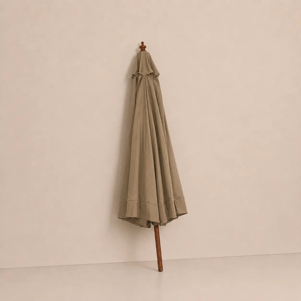 Taupe market umbrella folded closed with hardwood pole and carved wooden finial