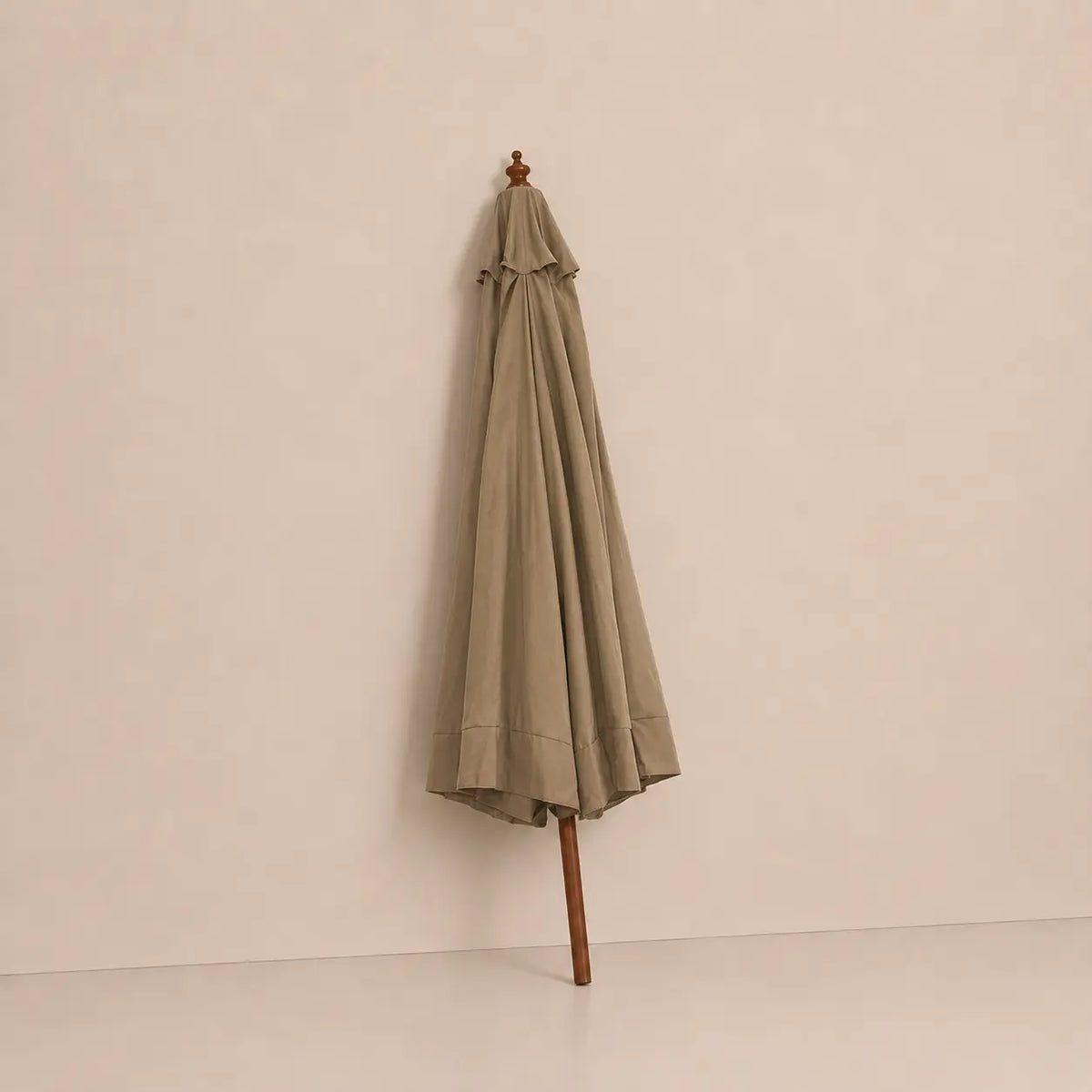 Taupe market umbrella folded closed with hardwood pole and carved wooden finial