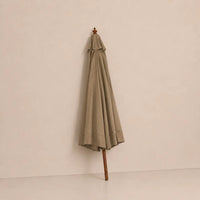 Taupe market umbrella folded closed with hardwood pole and carved wooden finial