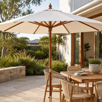 Sand market umbrella with vented hardwood pole shading an outdoor dining table on an Australian stone terrace