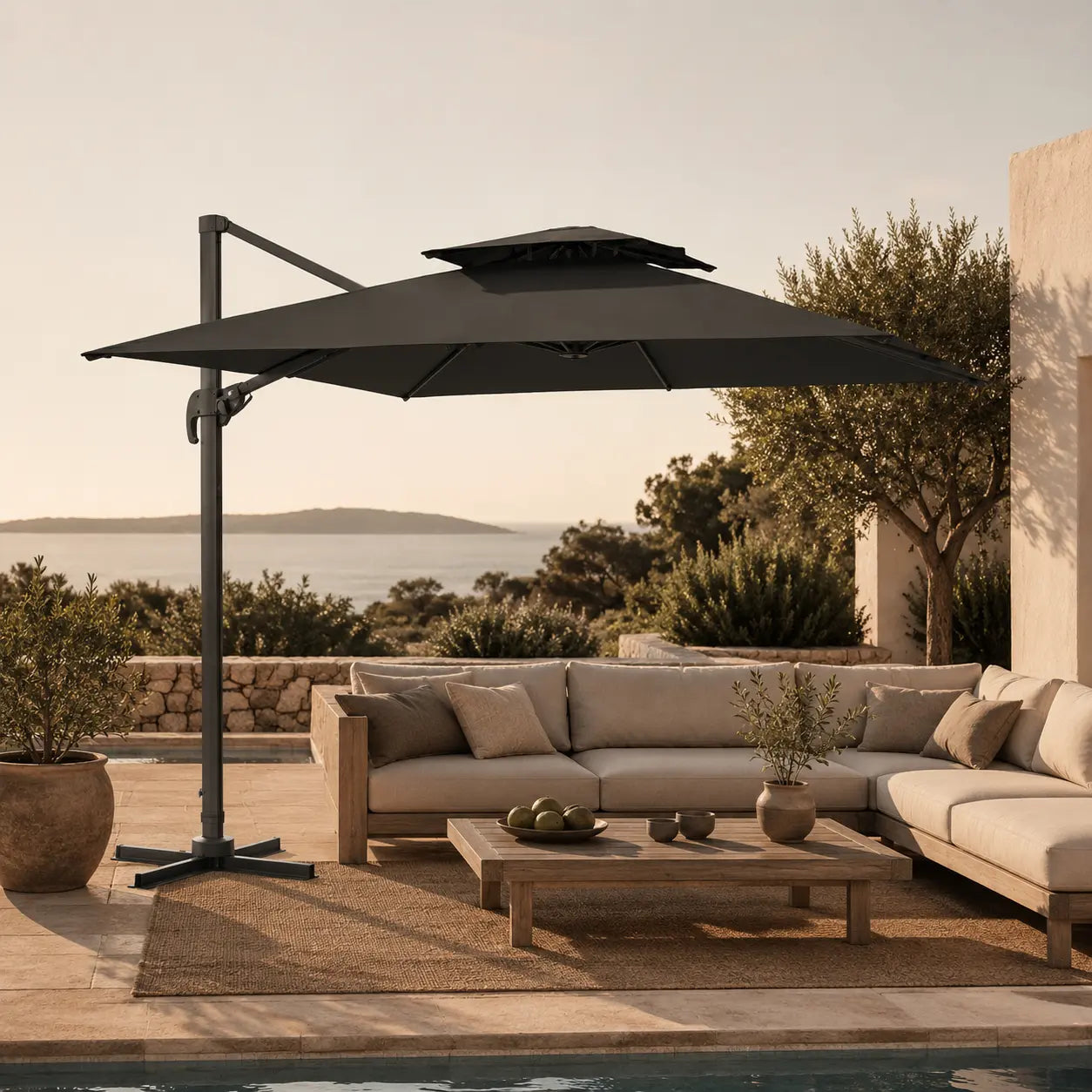 Anthracite cantilever umbrella 3x3m with vented double canopy shading an outdoor lounge setting at sunset by the sea