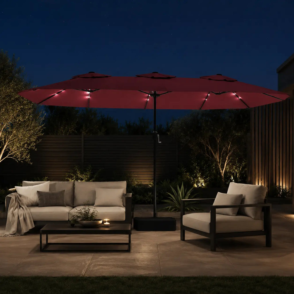 Large bordeaux double canopy market umbrella with LED lights over an outdoor lounge area in a garden setting at night