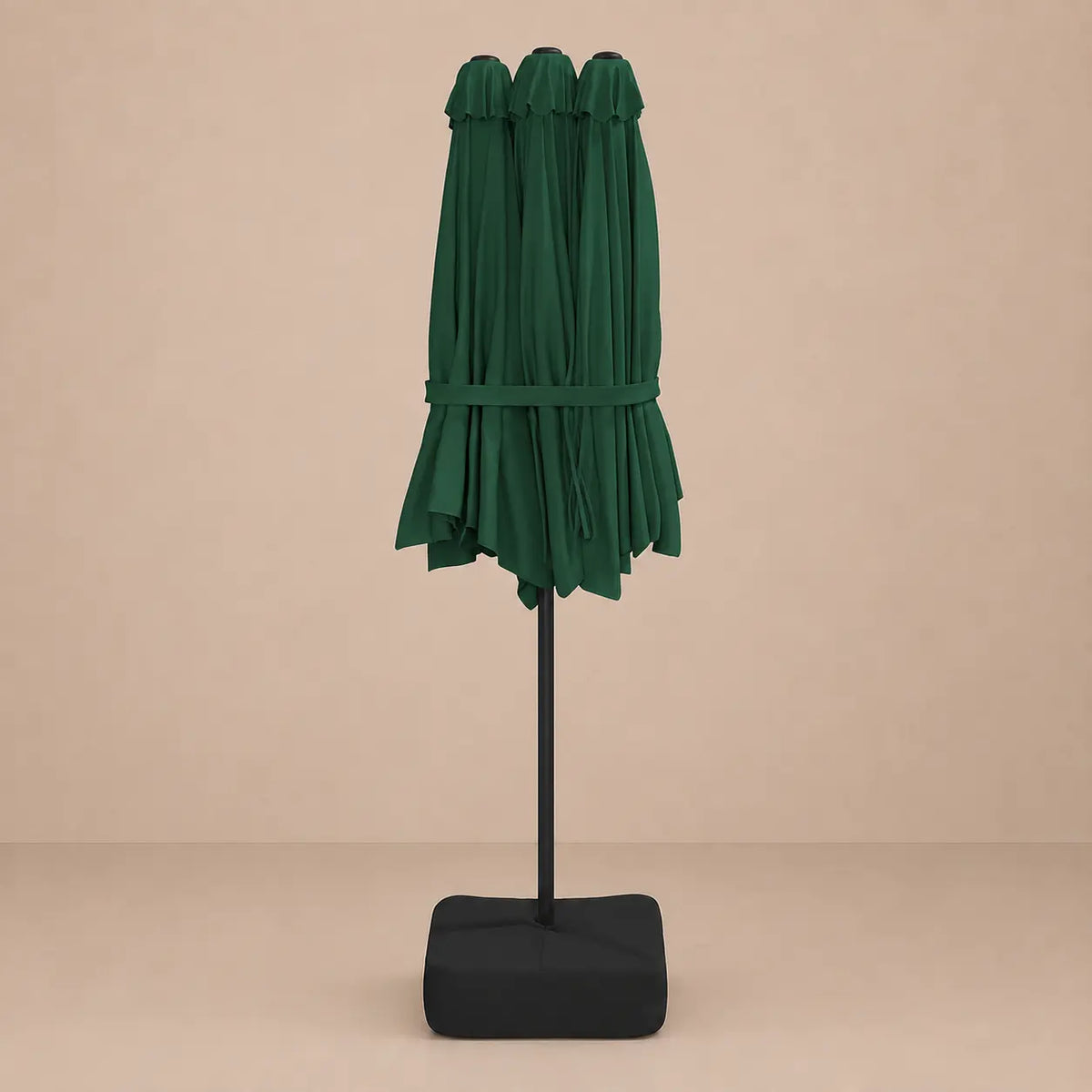 Green double canopy market umbrella folded closed on black aluminium pole with square weighted base