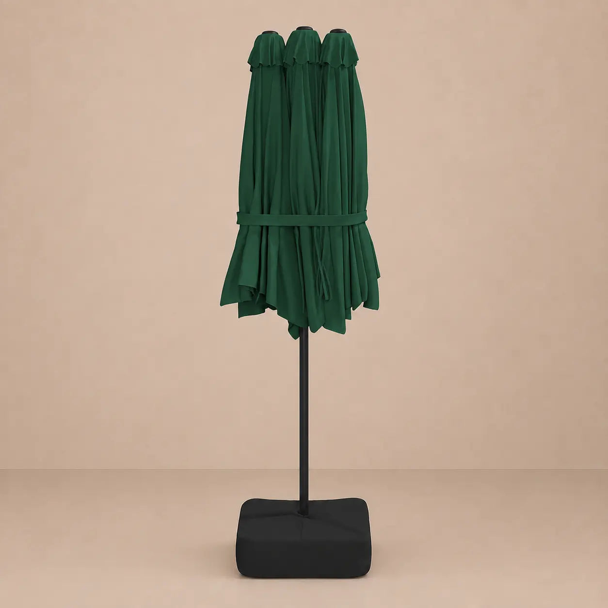 Green double canopy market umbrella folded closed on black aluminium pole with square weighted base