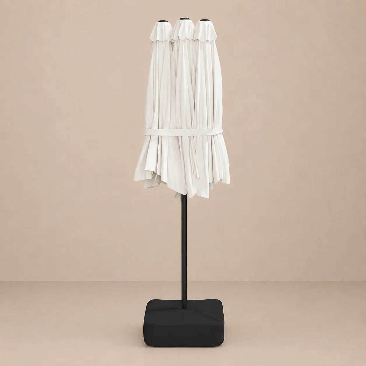 Sand white double canopy market umbrella folded closed on black aluminium pole with square weighted base