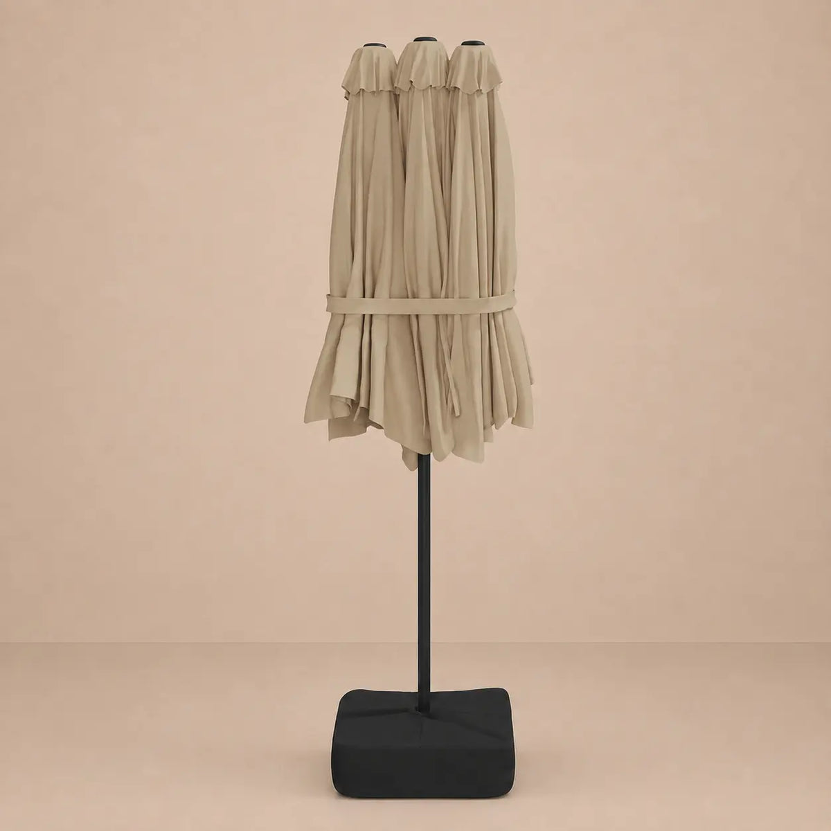 Taupe double canopy market umbrella folded closed on black aluminium pole with square weighted base