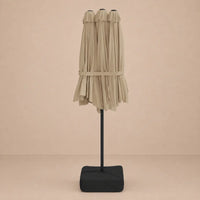Taupe double canopy market umbrella folded closed on black aluminium pole with square weighted base