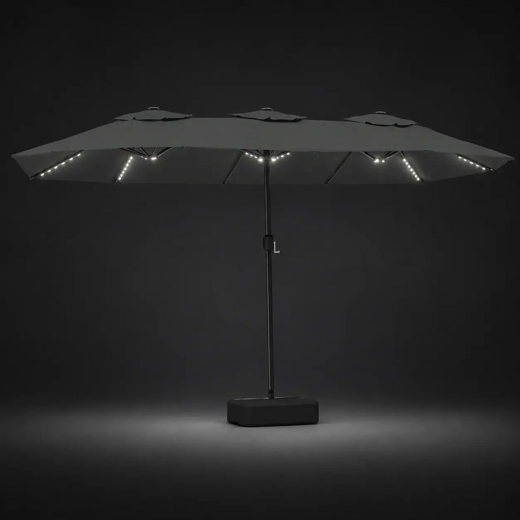 Anthracite double canopy market umbrella with integrated LED lights illuminated at night on a dark background