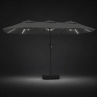 Anthracite double canopy market umbrella with integrated LED lights illuminated at night on a dark background