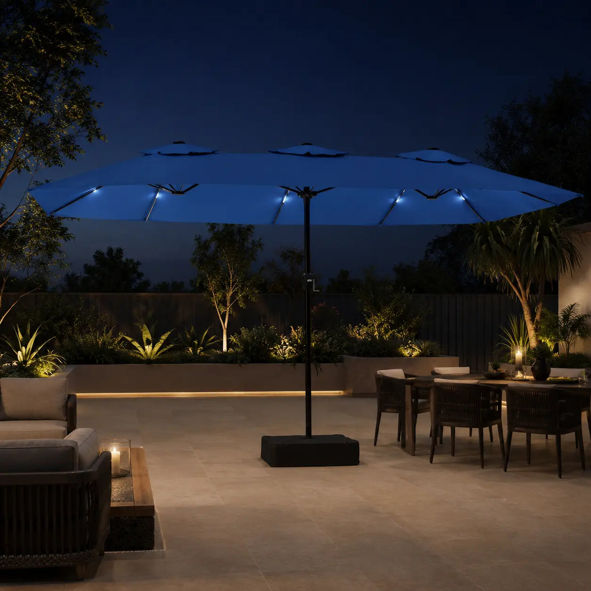 Large azure blue double canopy market umbrella with LED lights over an outdoor lounge and dining area at night