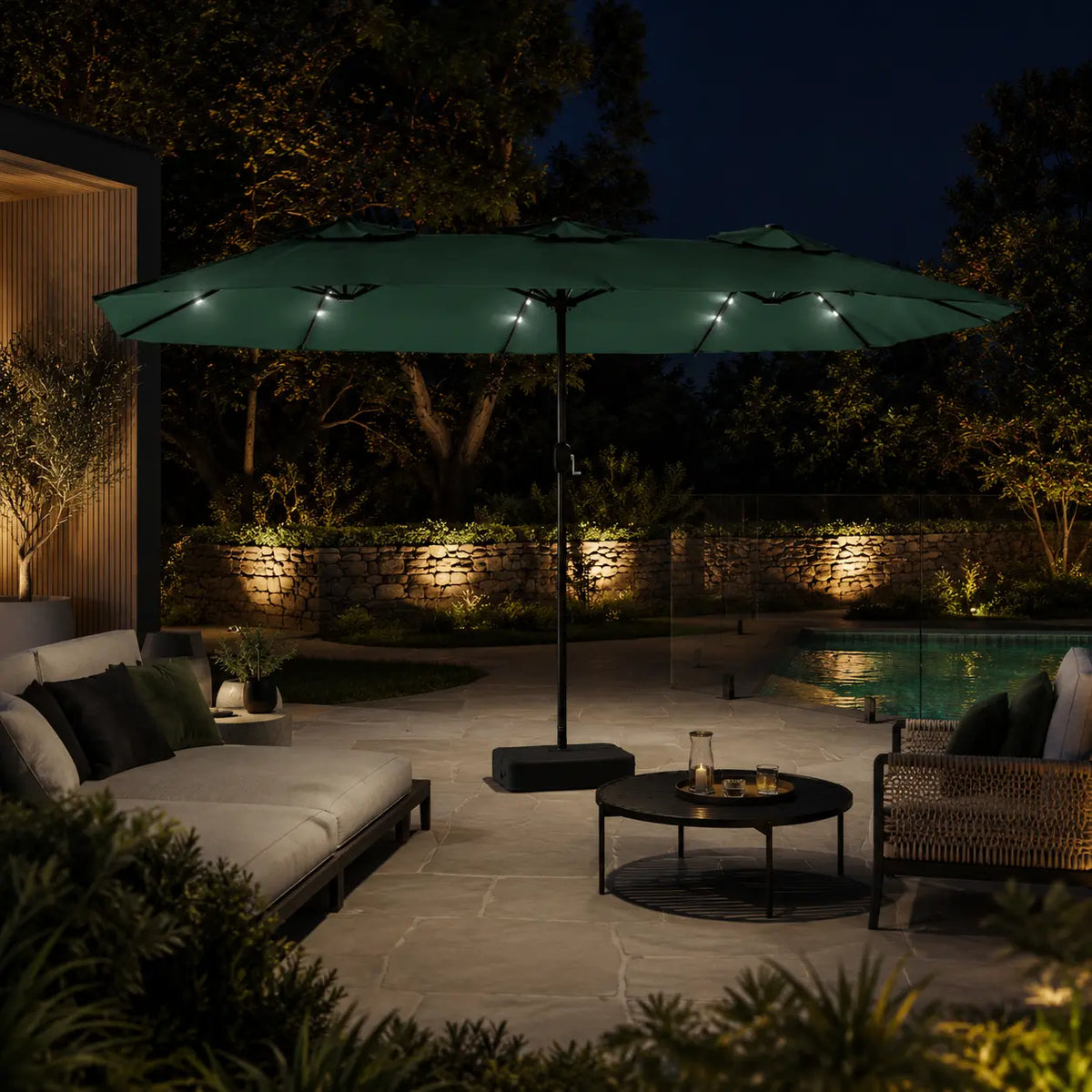 Large green double canopy market umbrella with LED lights over an outdoor lounge area beside a pool at night