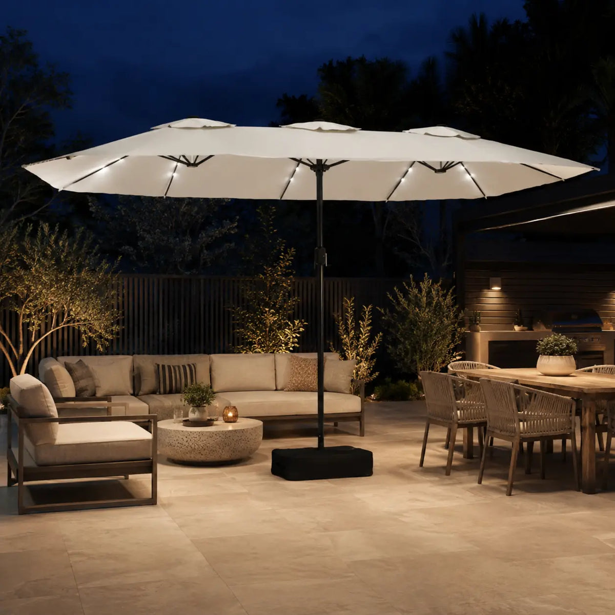 Large double canopy market umbrella with LED lights over an outdoor lounge and dining area at night