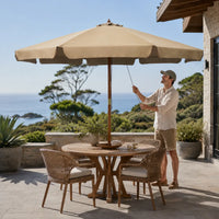 Taupe market umbrella set up over a round outdoor dining table on a coastal Australian deck