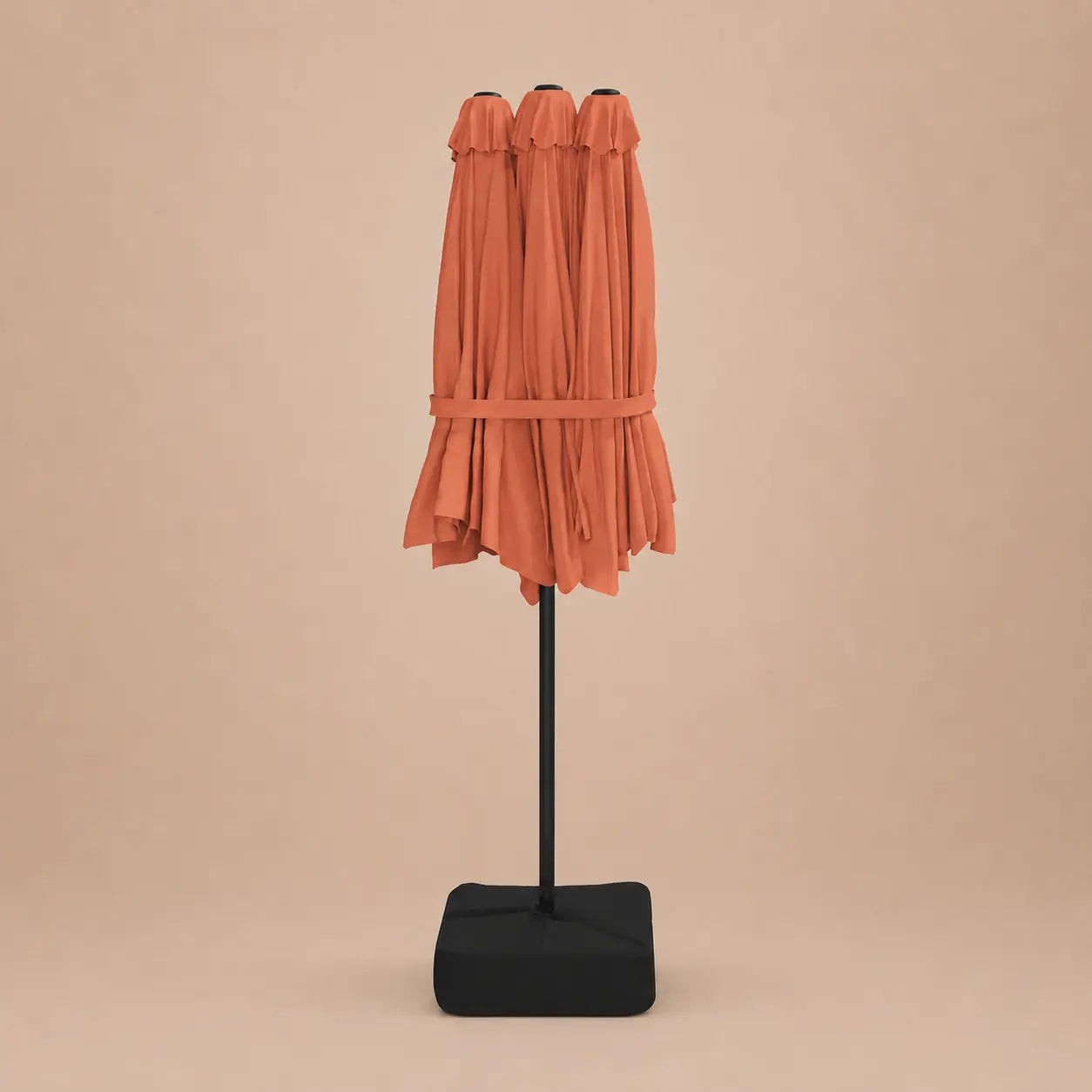 Terracotta double canopy market umbrella folded closed on black aluminium pole with square weighted base