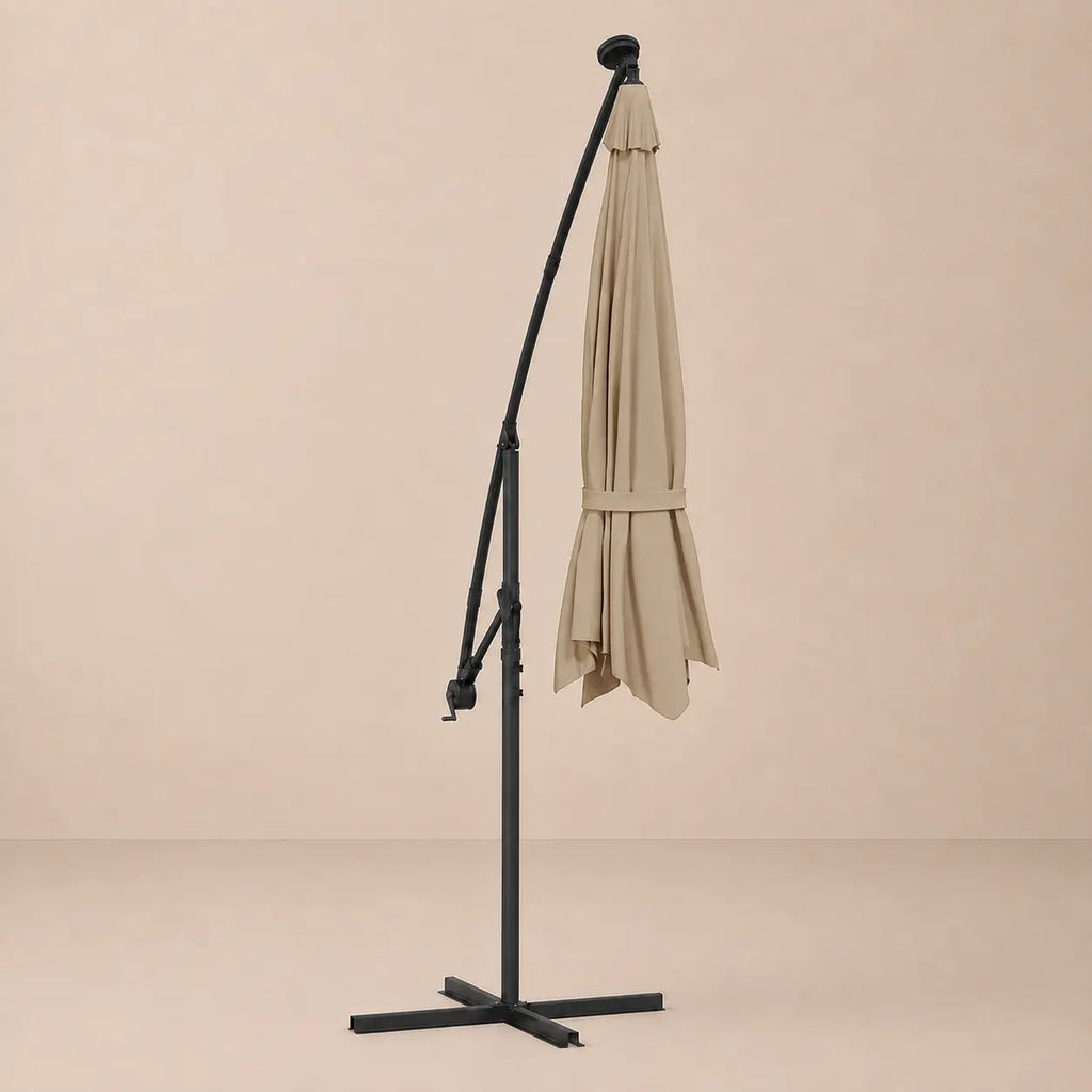 Round cantilever umbrella 3m Taupe folded and secured with carry strap on cross stand with solar panel – Meltem