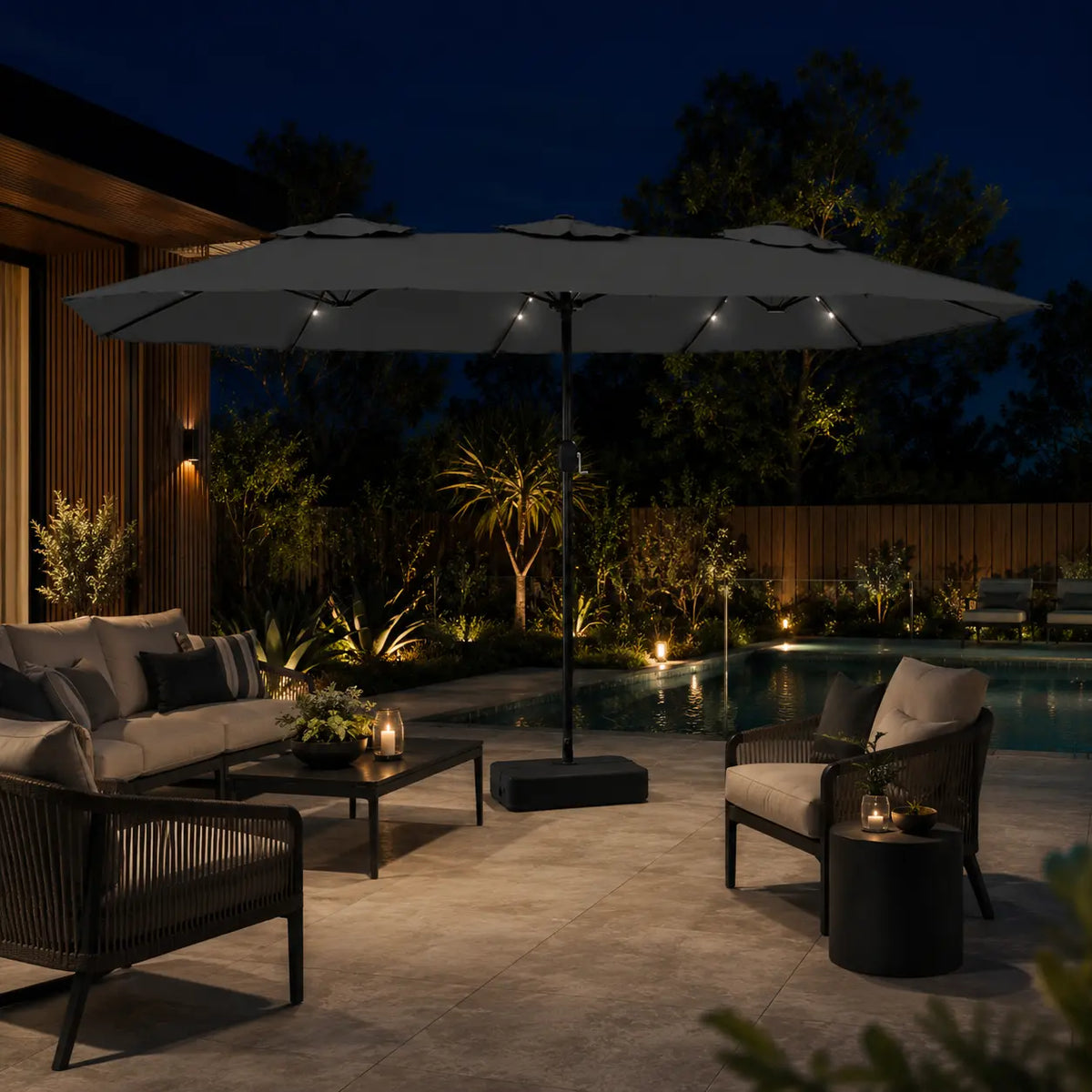 Large anthracite double canopy market umbrella with LED lights over an outdoor lounge area beside a pool at night