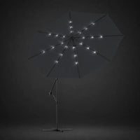 Round cantilever umbrella 3m Black with solar LED lights illuminated along ribs at night – Maestro