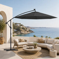 Round cantilever umbrella 3m Anthracite over curved outdoor sofa on villa patio with sea-view hillside – Libeccio